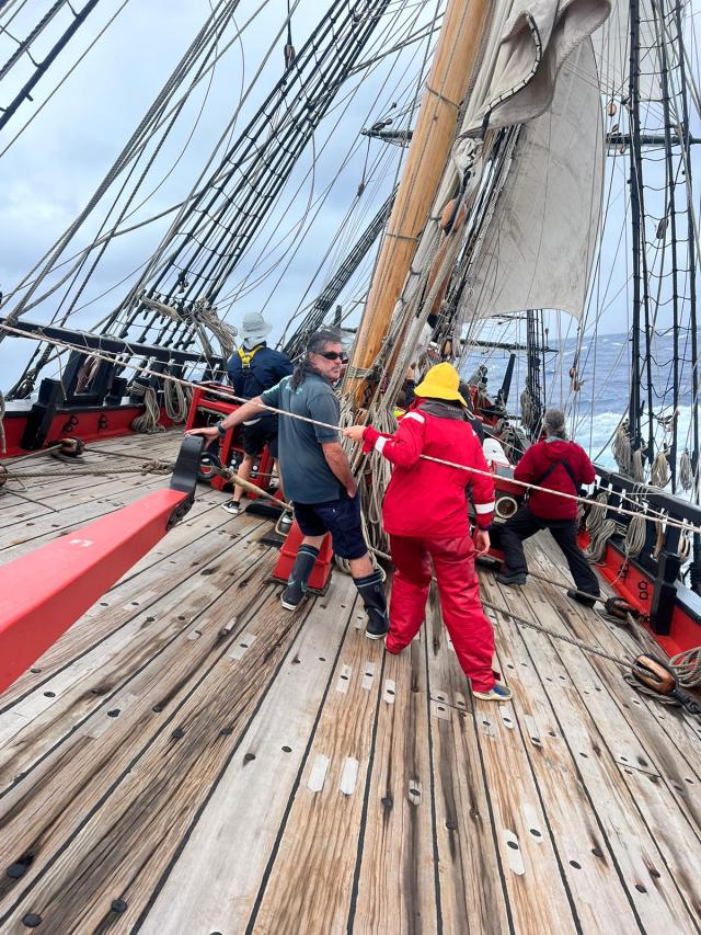 Photo of crew members working aboard Endeavour tall ship with deck at an angle