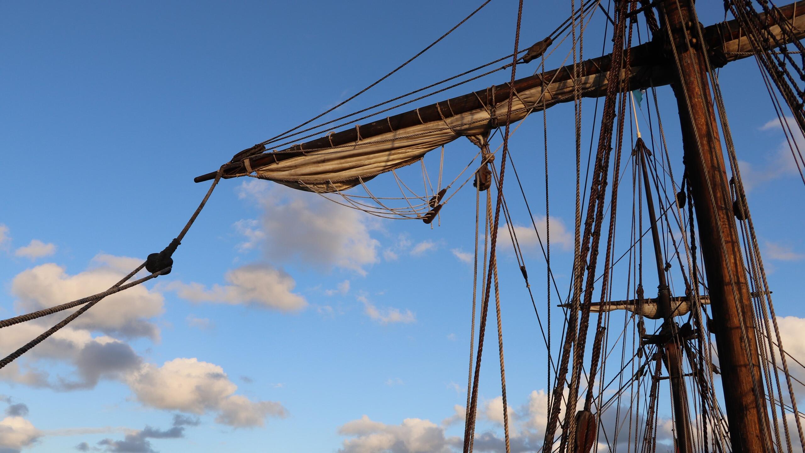 tall ship masts and rope with blue sky and clouds